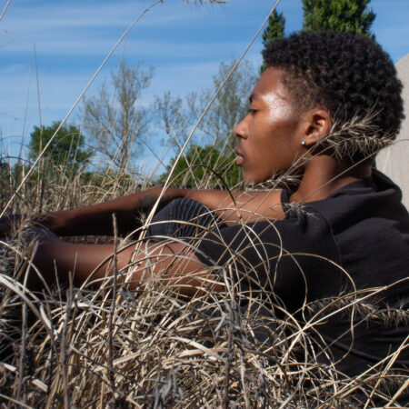 a Black man sitting in a field