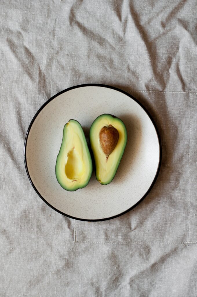 An avocado split in half with the fruit facing up on both sides, sitting on a plate 