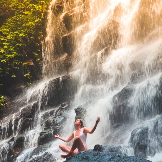 Woman sitting in front of waterfall calmly