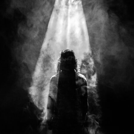 dark figure standing in beam of light